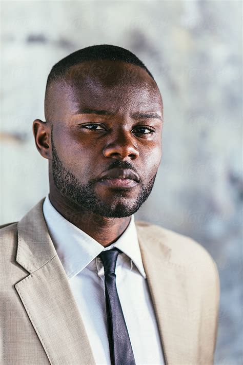 Portrait Of A Black Businessman Standing In Front A Grey Wall By