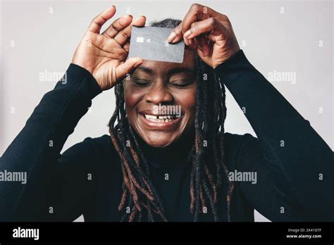 Mature Woman With Dreadlocks Smiling Happily While Holding A Credit Card Over In Front Of Her