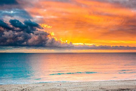 Pink And Orange Sunset With A Dark Blue Cloud On The Left The Ocean