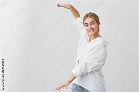 Amazed Blonde Girl In White Shirt Showing With Hands Length Of Box Pretty Female Wearing Casual