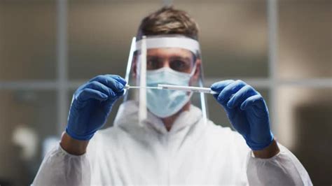 Caucasian Male Medical Worker Wearing Protective Clothing And Face Shield Inspecting Dna Swab In