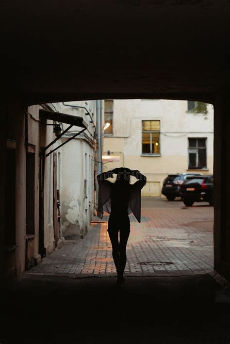 Silhouette Of Woman Walking Down A Street In Tunnel In Rainy Weather