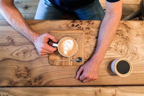 Premium Photo Mans Hands Hold A Cup Of Cappuccino Coffee On A Wooden