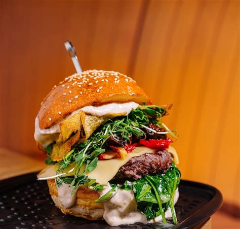 Premium Photo Gourmet Burger With Fresh Toppings On Wooden Table