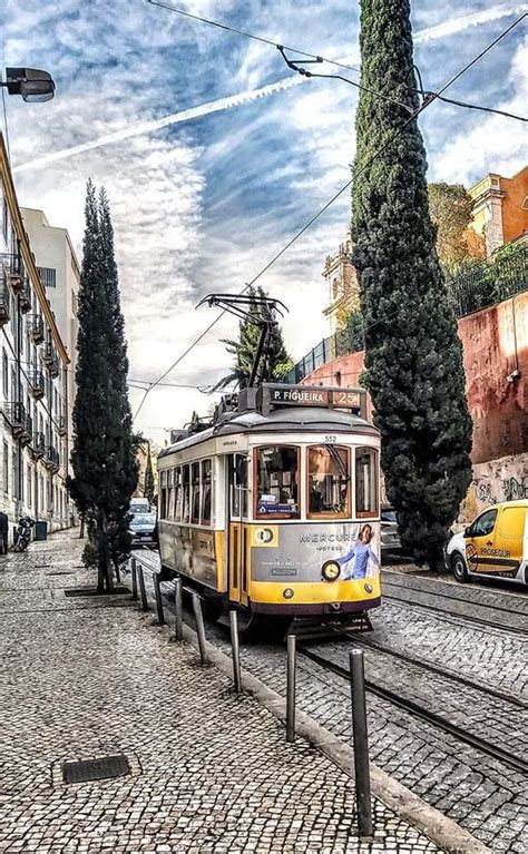 A Yellow And White Trolley Car Traveling Down A Street Next To Tall