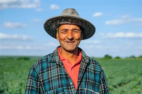 The Portrait Of A Male Farmer In A Plaid Shirt With A Hat On His Head