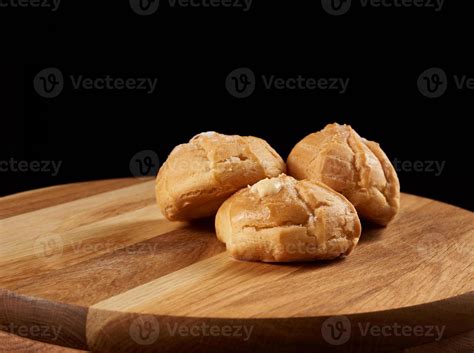 Baked Custard Eclairs And Sprinkled With Powdered Sugar On A Brown Wooden Board 17469426 Stock