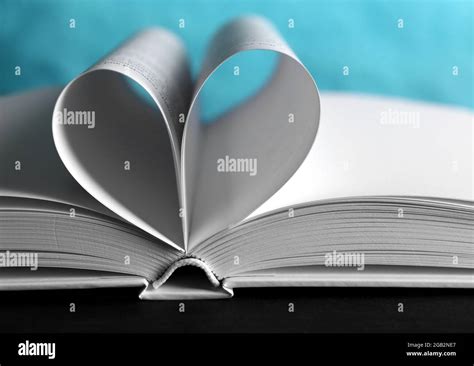 Sheets Of Book Curved Into Heart Shape On Unfocused Blue Background