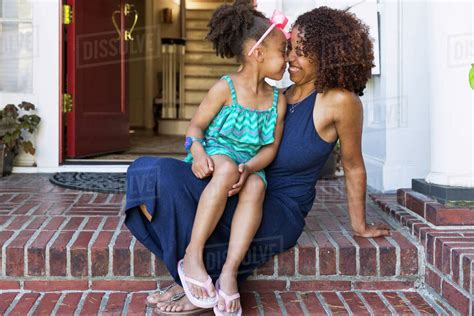 Smiling Mixed Race Mother And Daughter Rubbing Noses On Front Stoop