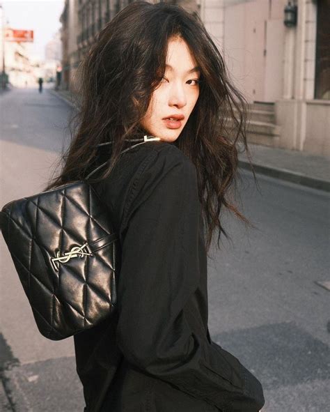 A Woman With Long Hair Carrying A Black Purse