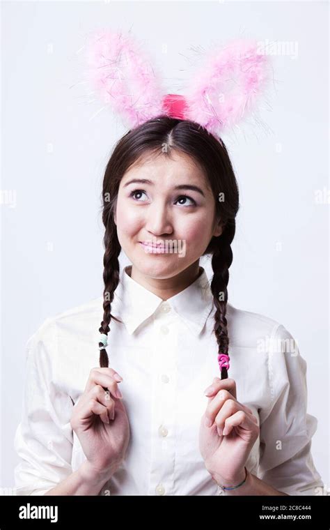 Cute Asian Girl Wearing Pink Bunny Ears And Holding Braided Hair Stock