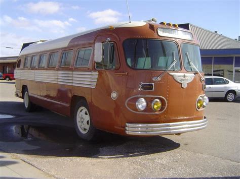 An Old Bus Parked In A Parking Lot Next To A Building With Cars Behind It