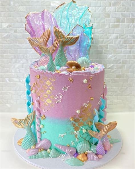 There Is A Cake Decorated With Mermaids And Seashells