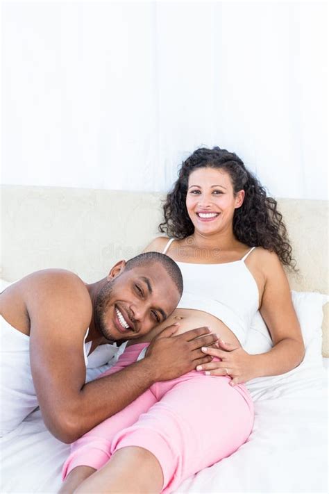 Retrato Do Homem Que Escuta a Barriga Da Esposa Grávida Feliz Na Cama