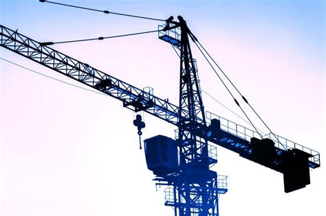 the silhouette of a crane against a blue sky