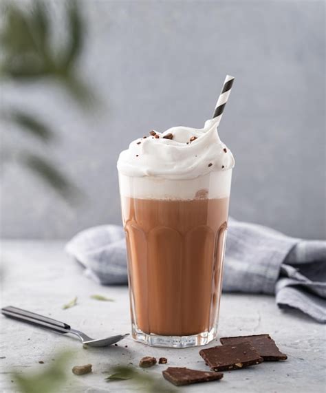 Premium Photo Hot Chocolate With Whipped Cream And Chocolate Pieces In A Tall Glass On A Blue