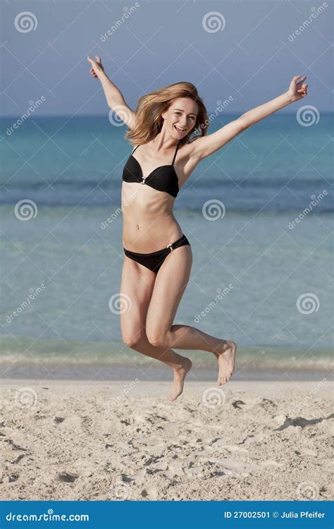 Woman With Bikini Jumping Happily On The Beach Portrait Stock Image