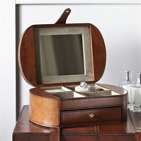 An Open Wooden Box With Two Rings Inside On Top Of A Table Next To Bottles