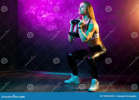 Focused Young Woman Fitness Model Doing Squats With Professional