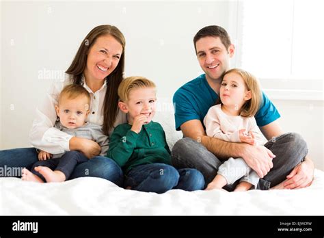 Retrato De Familia Con Tres Hijos Sentada En La Cama