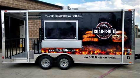 a food trailer parked in front of a building with flames on the door ...