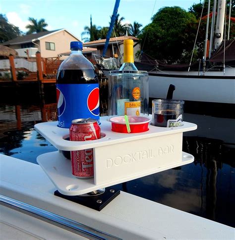 A Bottle Of Booze And Some Drinks On A Tray Near A Boat In The Water