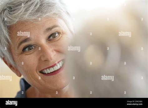 Mature White Haired Woman Checking Eye Wrinkles In Front Of Mirror