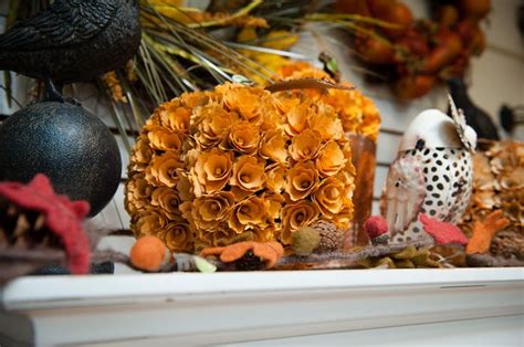 An Assortment Of Fake Flowers And Birds On A Mantle With Other