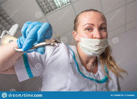 De Artsenvrouw In Een Medisch Masker En Met Forceps In Haar Handen