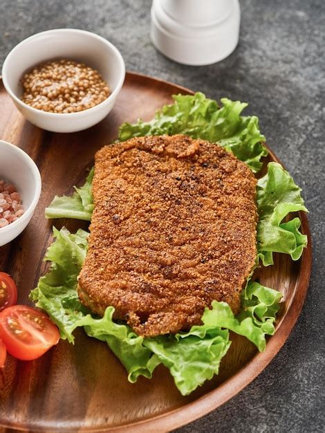 Chuleta De Cerdo Rebozada Con Tomates Cherry Mostaza Y Limón Foto