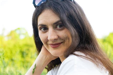 Portrait Of A Year Old Brunette Woman Looking At The Camera Smiling In Nature Stock Photo