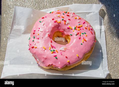 Large Pink Iced Donut On A Paper Bag Stock Photo Alamy