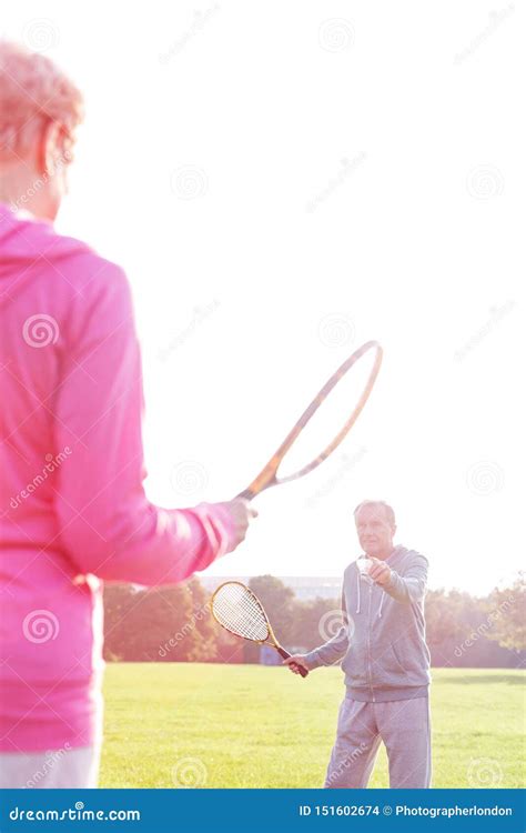 Senior Man And Woman Playing Badminton With Tennis Bats In Park Stock