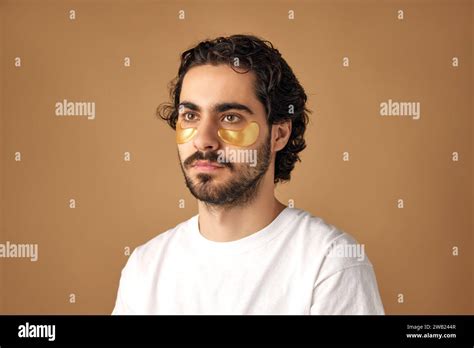 Portrait Of Calm Brunette Man With Beard Applying Hydrogel Patches With