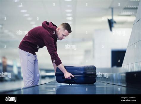 Traveling By Airplane Passenger Pick Up His Blue Suitcase In Baggage