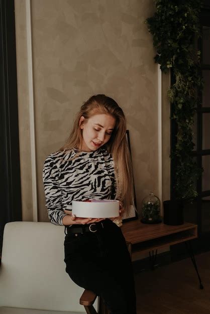 Premium Photo A Girl With Blonde Hair Is Sitting On A White Armchair In Astriped Black And