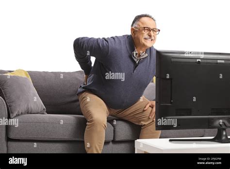 Mature Man With Back Pain Getting Up From A Sofa In Front Of Tv