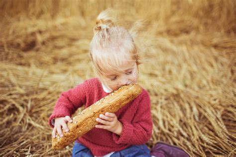 Une Fille Assez Petite Mangent D Un Pain Sur Un Champ Photo Stock