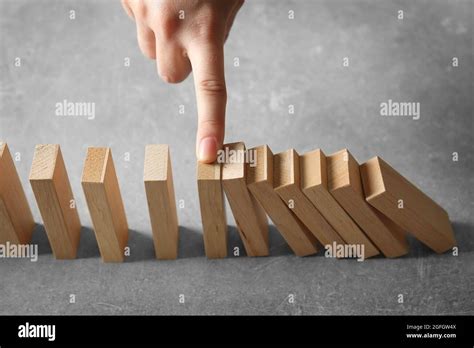 Female Hand Stopping Domino Effect On Grey Background Stock Photo Alamy