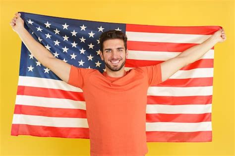 Homem caucasiano feliz levantando uma bandeira nacional da américa do