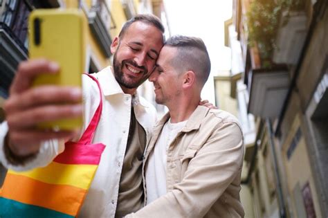 Una pareja gay tomando una foto con su teléfono celular en una actitud romántica en la calle
