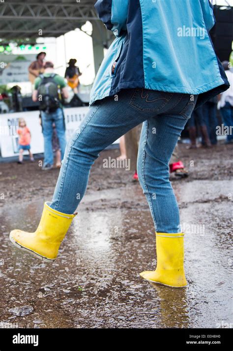 Woman Wearing Yellow Rain Boots At River Fest Splashing In Puddle