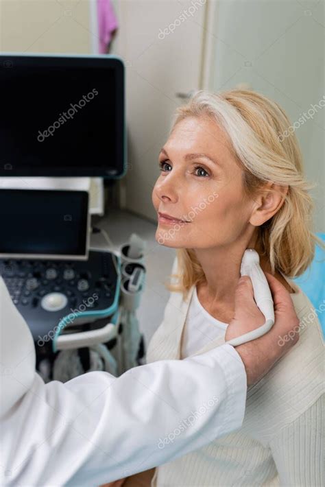 mujer rubia sonriendo cerca del médico haciendo ultrasonido de sus