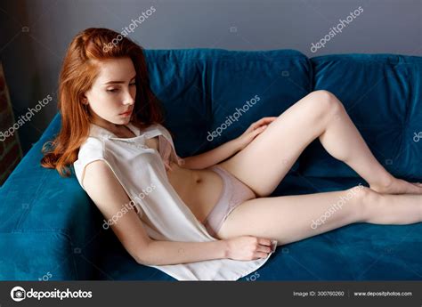 Half Naked Redhead Woman Resting On The Blue Couch At Home Stock Photo