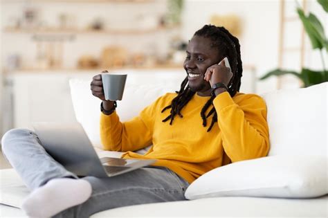 Premium Photo Cheerful Black Man Talking On Mobile Phone And Drinking