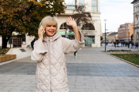 Portrait Of Smiling Caucasian Woman Talking On Phone And Waving Her