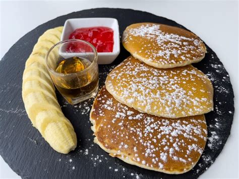 Panqueques con azúcar en polvo rodajas de plátano mermelada de fresa