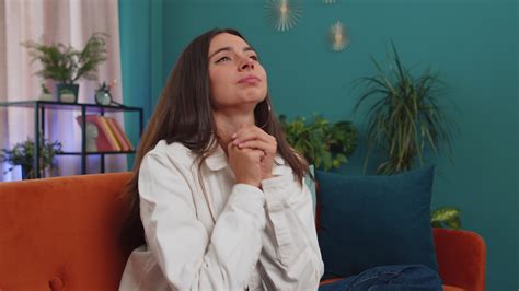 Young woman praying sincerely with folded arms asking God for help