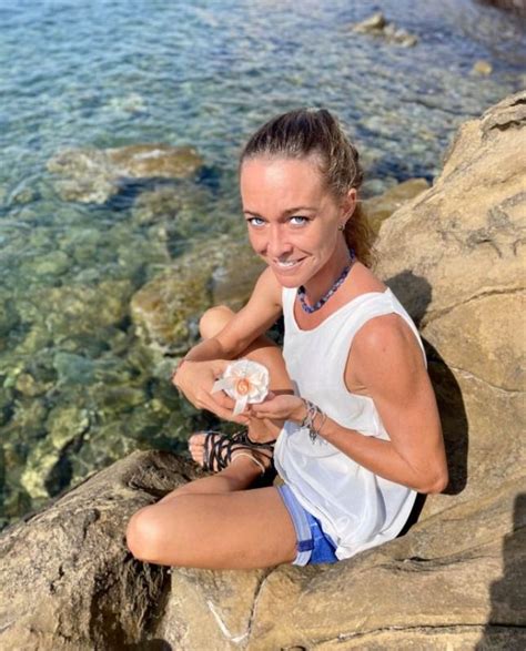 A Woman Sitting On Top Of A Rock Next To The Ocean Holding A Donut