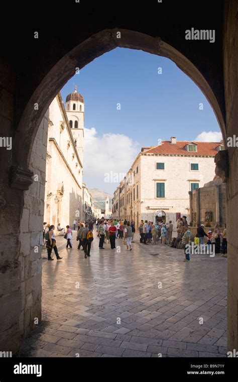 View Through Pile Gate With Tourists And Visitors Strolling Along Placa